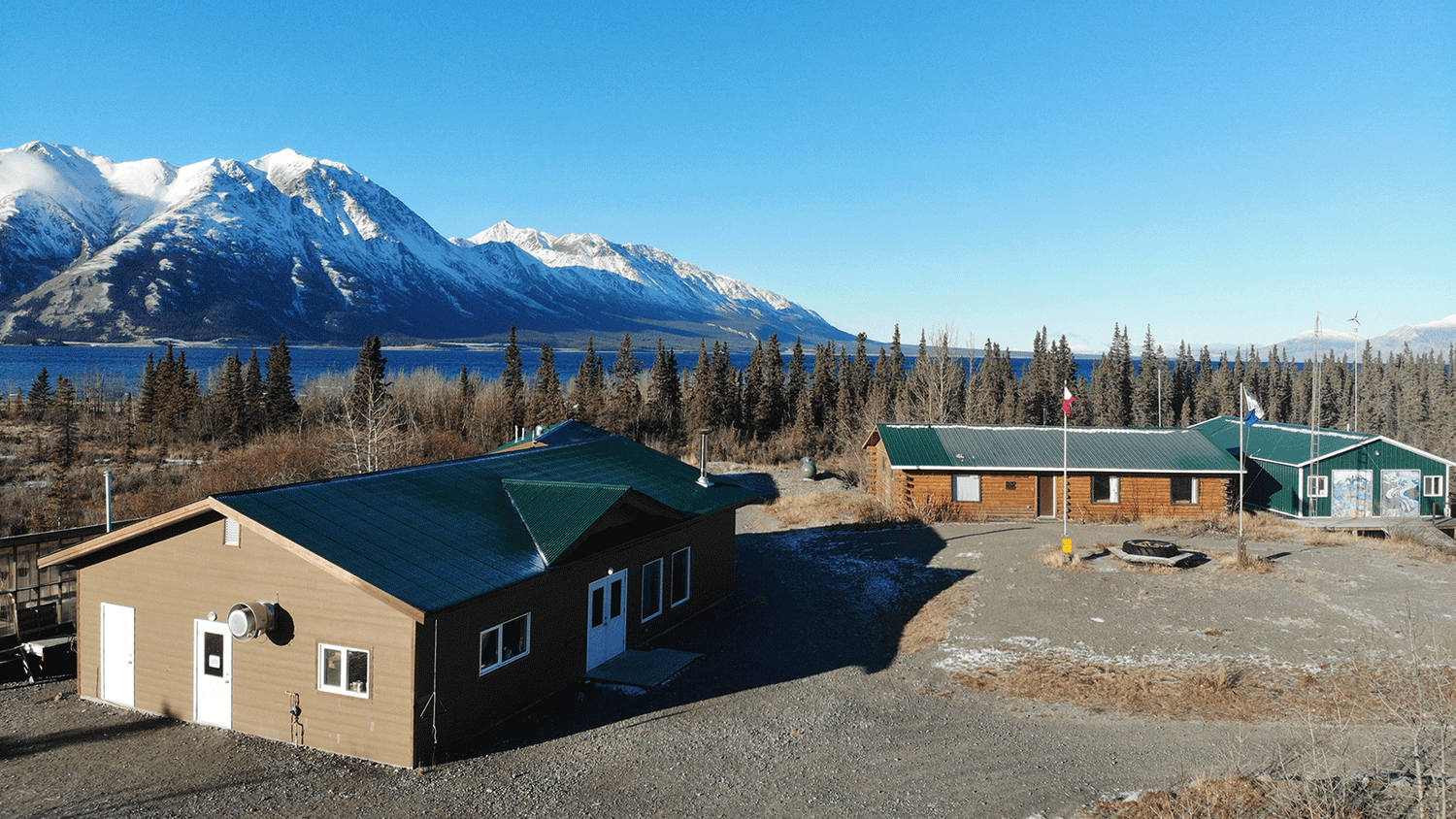A set of low-rise buildings, with a scenic background of mountains and a lake.